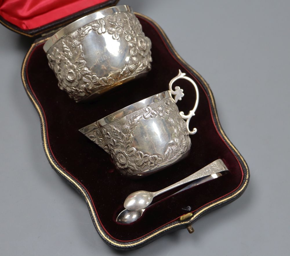 A cased late Victorian embossed silver cream jug, sugar bowl and pair of tongs